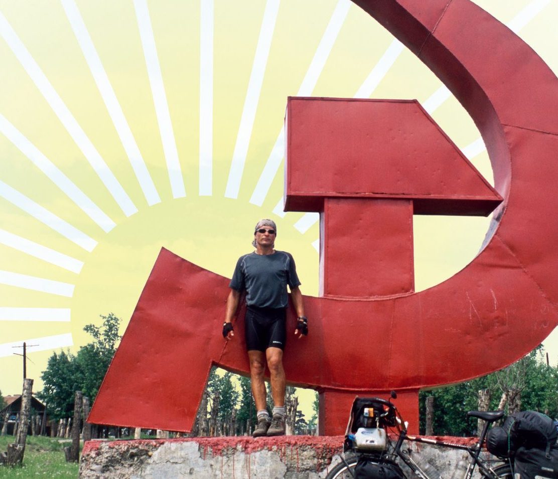 Ausschnitt vom Titelbild zu Diashow "Der Sonne entgegen - Wladiwostok", Reiseimpressionen von Thomas Meixner. Zu sehen sind der Autor mit Fahrrad vor Hammer und Sichel in Russland.